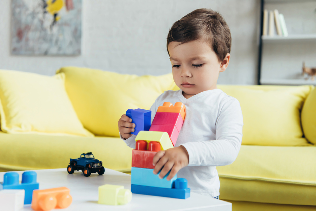 Little boy playing with colorful constructor blocks 