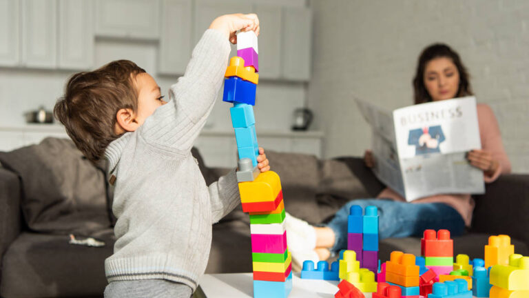 Little boy playing with colorful constructor blocks