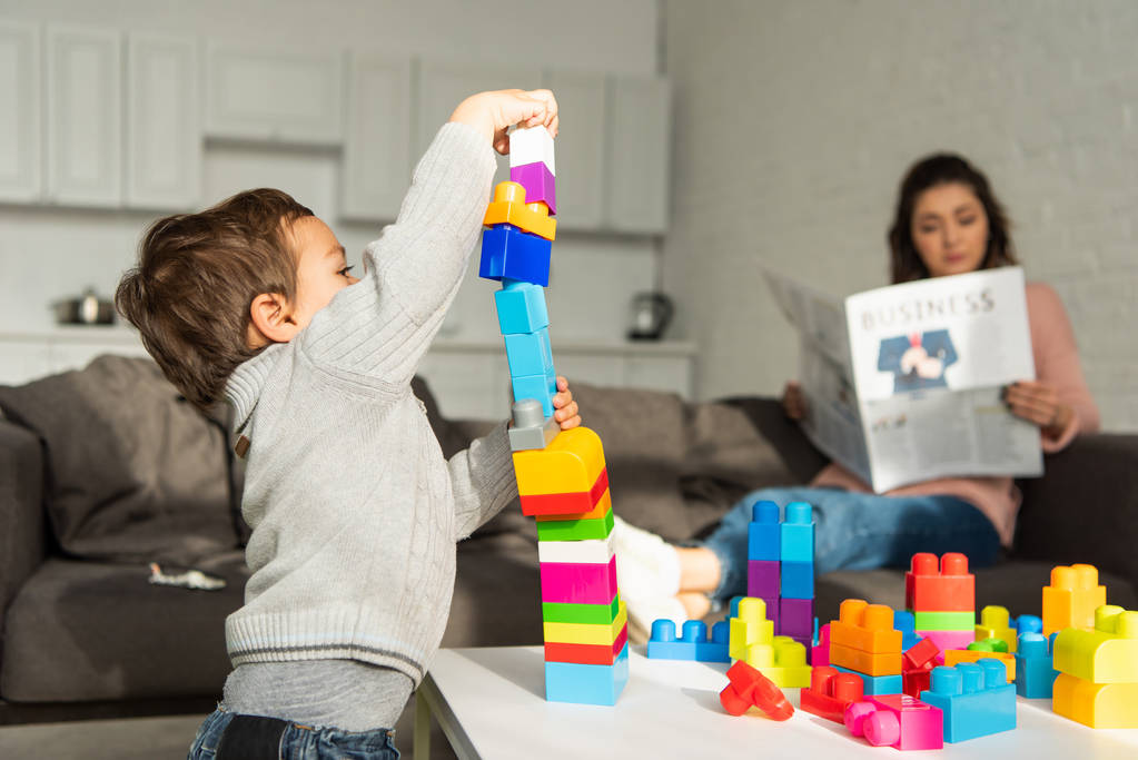Little boy playing with colorful constructor blocks