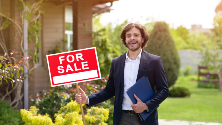 real estate agent holding FOR SALE sign
