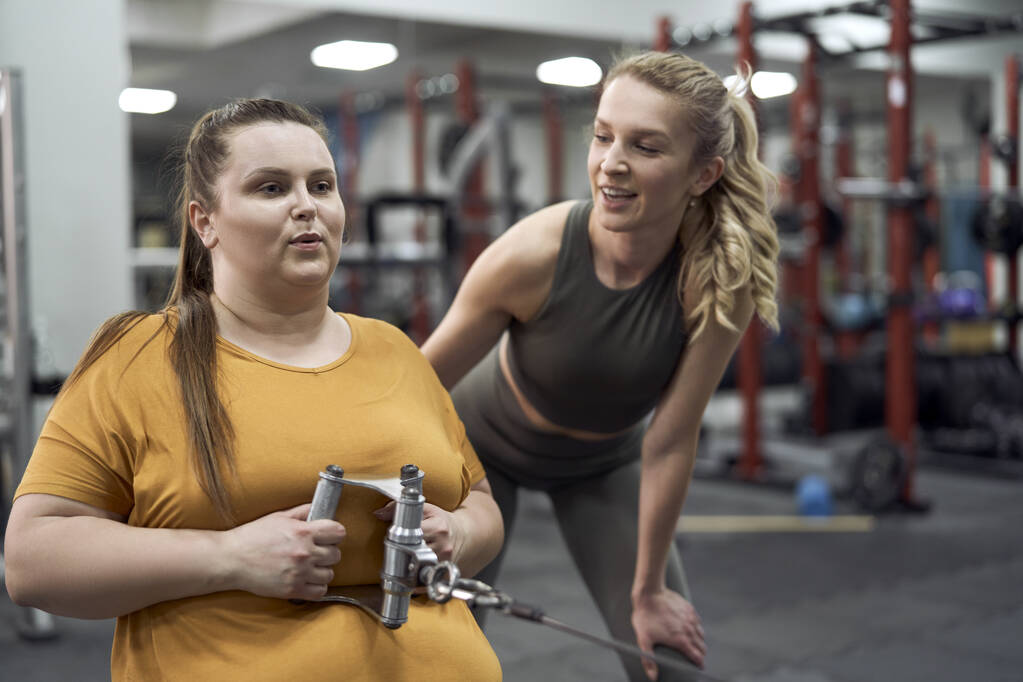plus size woman with her trainer at the gym