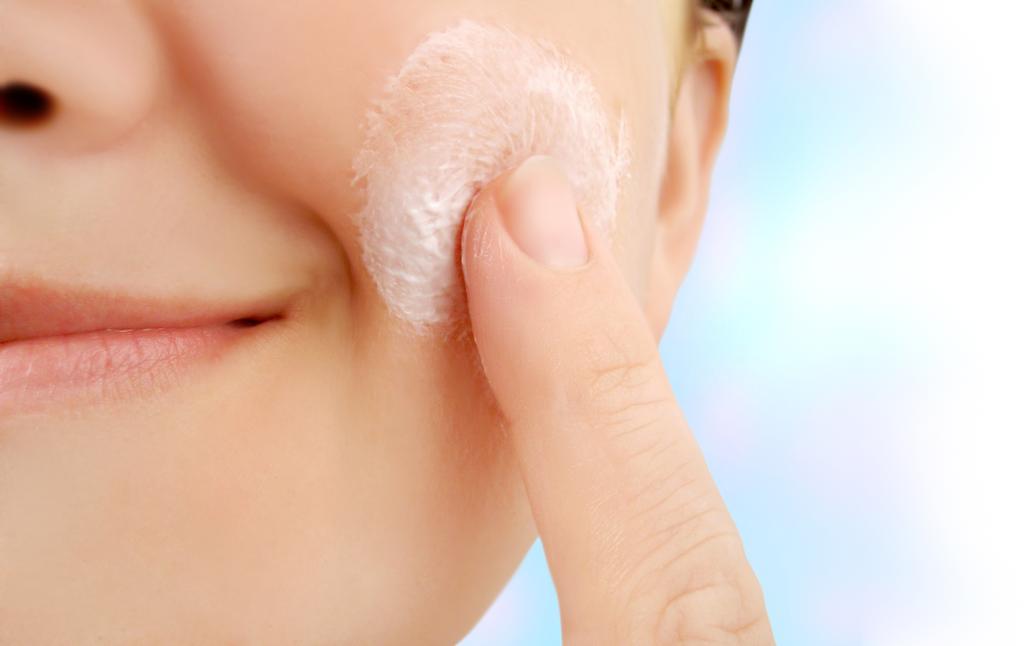 woman applies moisturizer onto face