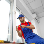 Young worker installing window in flat